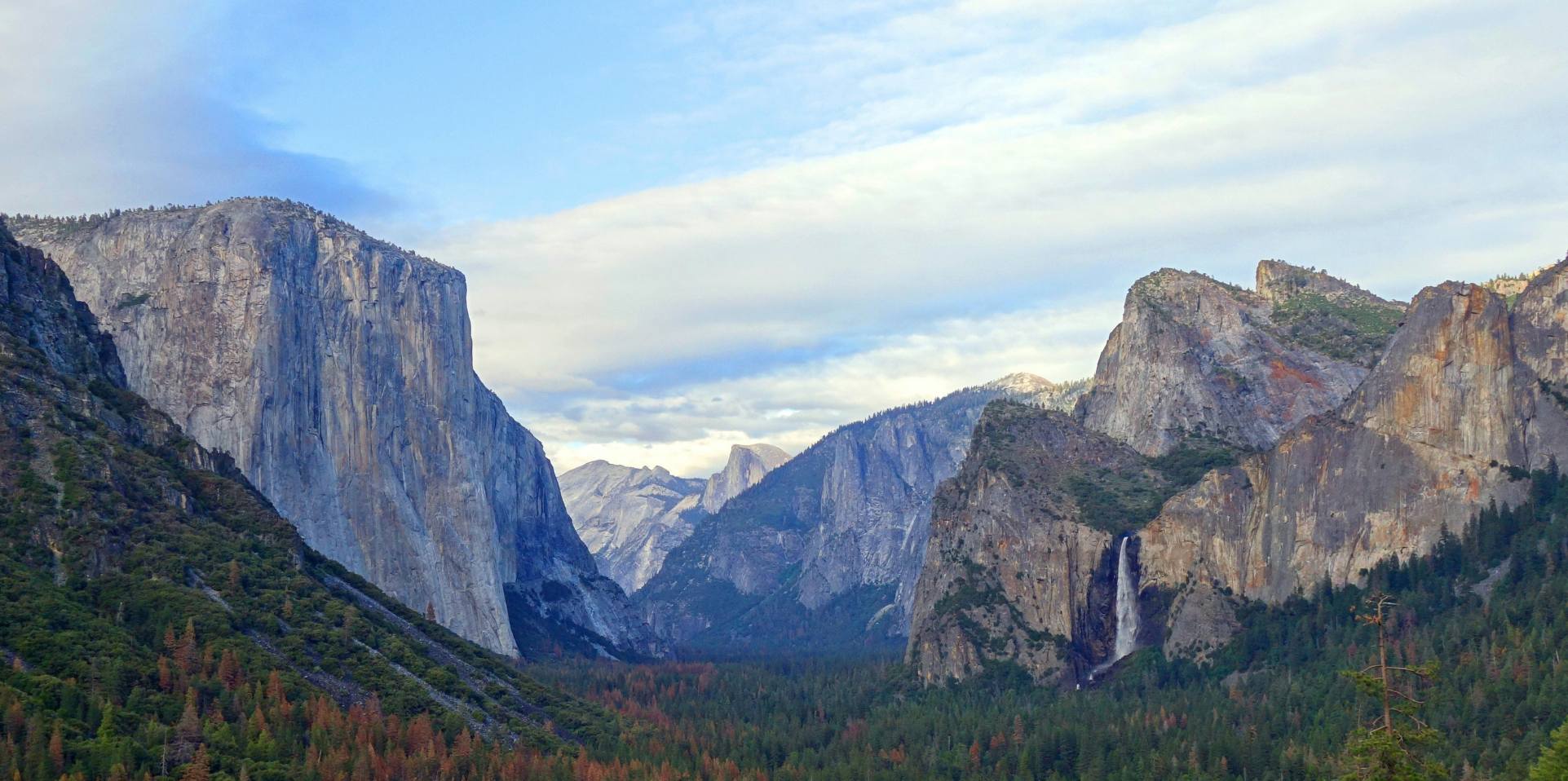 Canyon rocks with bright sky above and green trees below