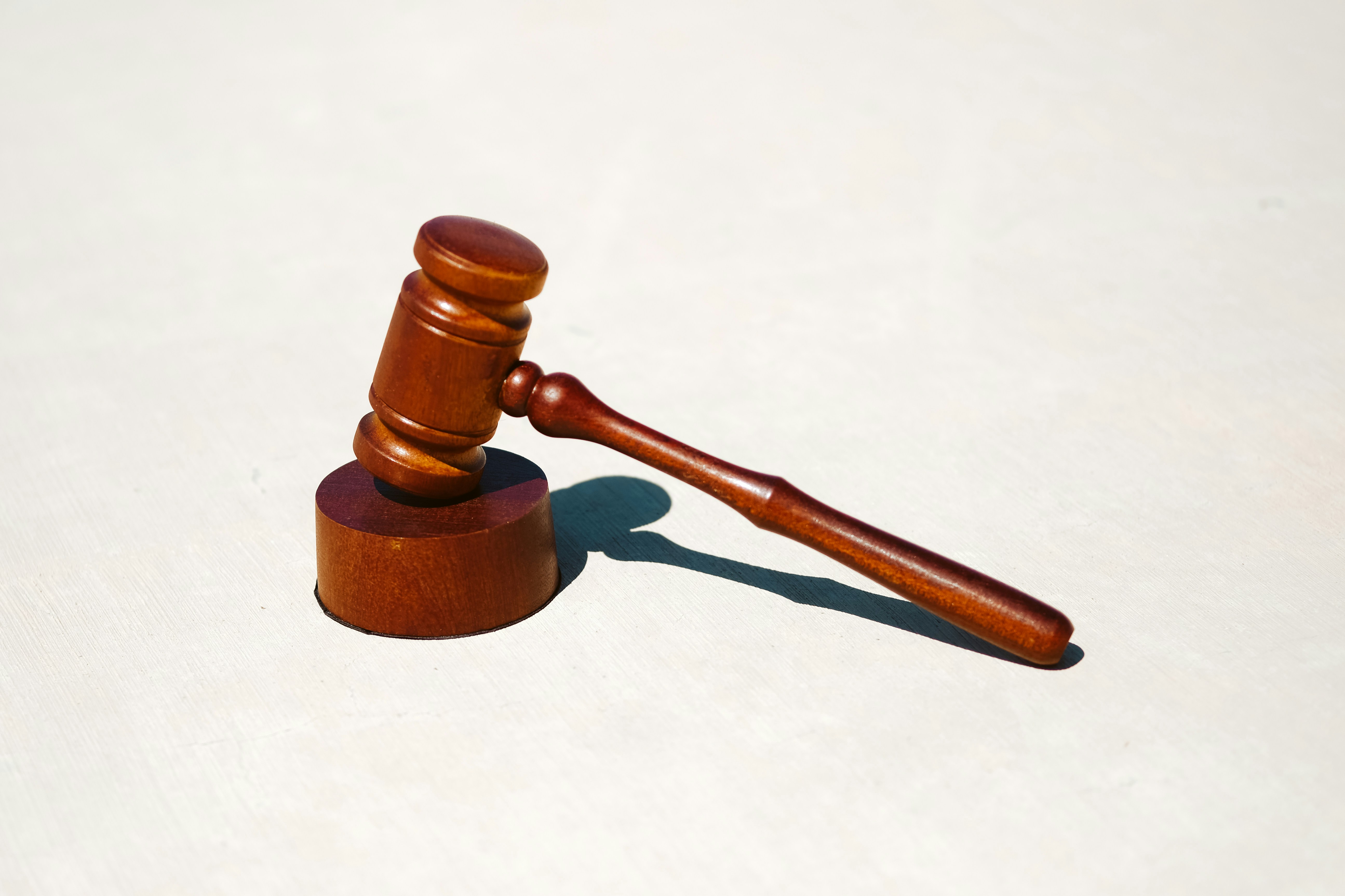 A brown gavel placed on top of its block on a cream background